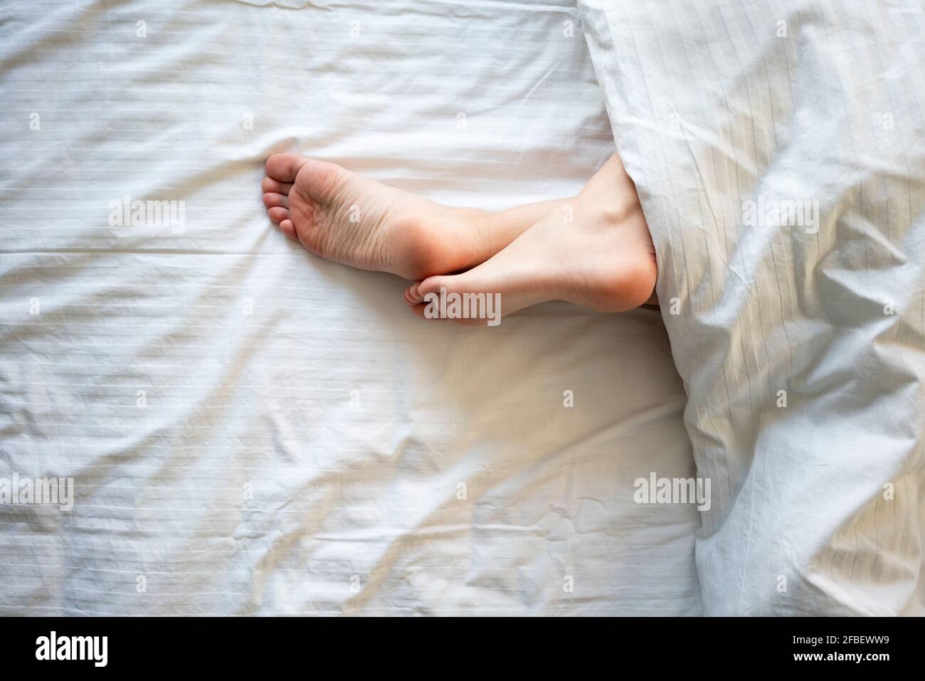 Femme jambes croisées à la cheville sur le lit Photo Stock - Alamy