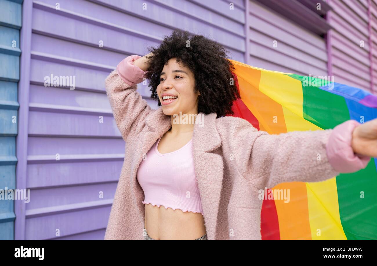 Belle femme souriant tout en tenant un drapeau multicolore Banque D'Images