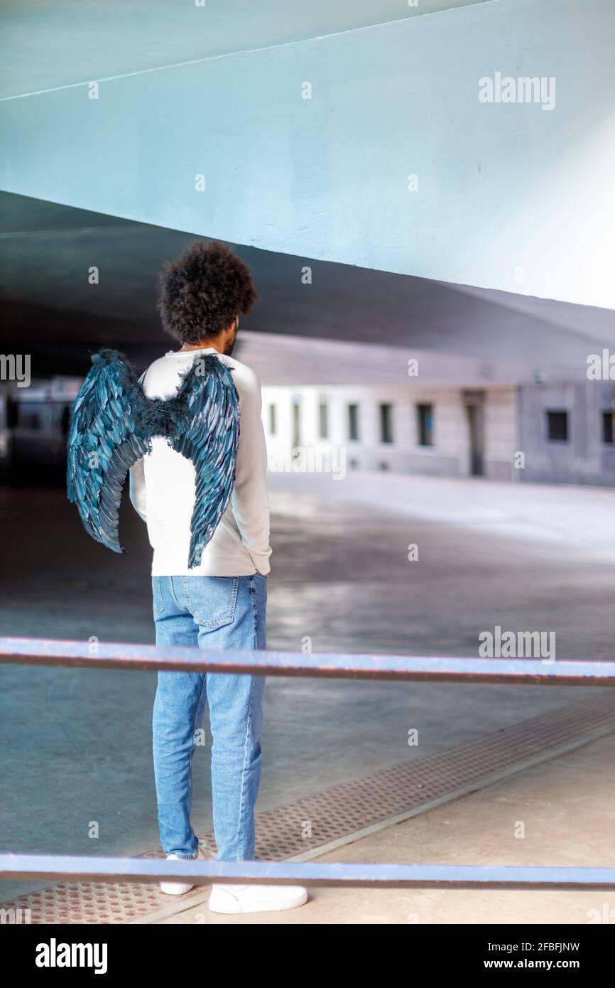 Jeune homme avec ailes d'ange regardant loin Banque D'Images