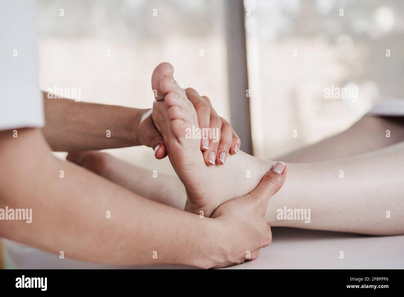 Thérapeute physique féminine effectuant un massage sur le pied du patient en clinique Banque D'Images