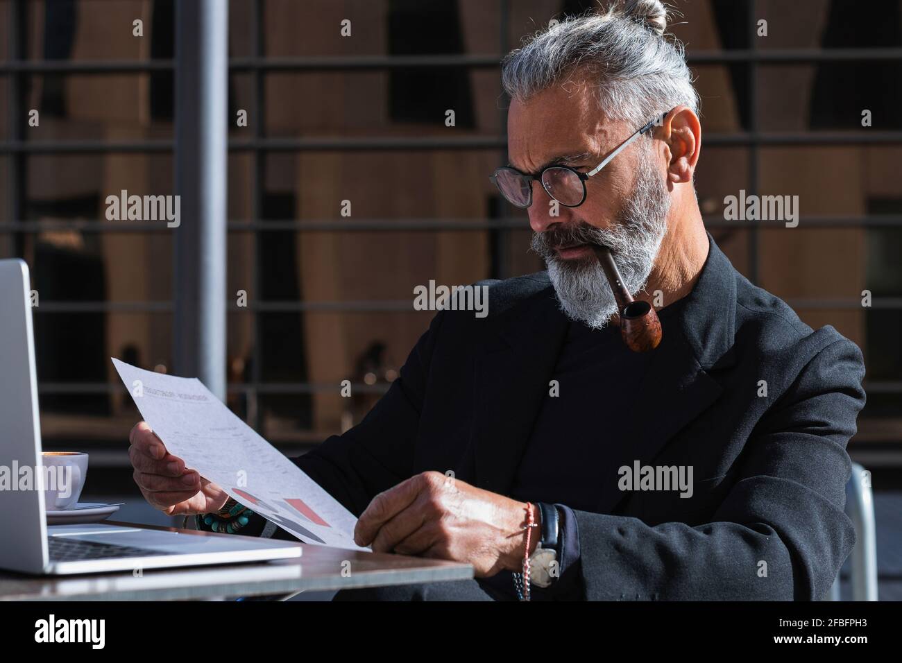 Homme entrepreneur sérieux regardant le plan d'affaires tout en étant assis café Banque D'Images