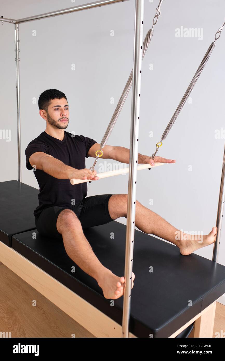 Athlète masculin pratiquant le pilates sur le reformeur dans la salle d'exercice Banque D'Images