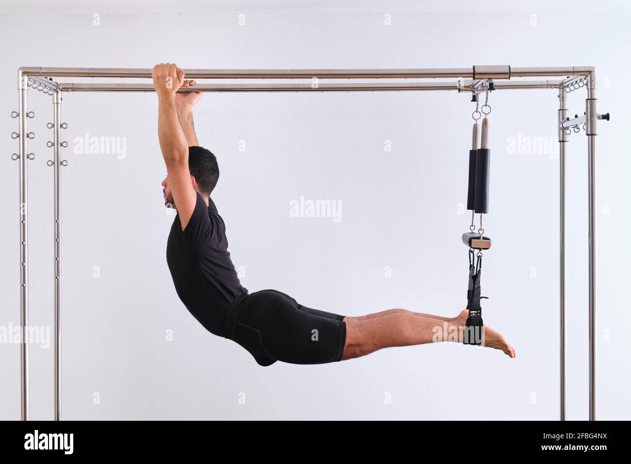 Homme faisant de l'exercice d'étirement tout en pratiquant pilates sur la table de trapèze Banque D'Images