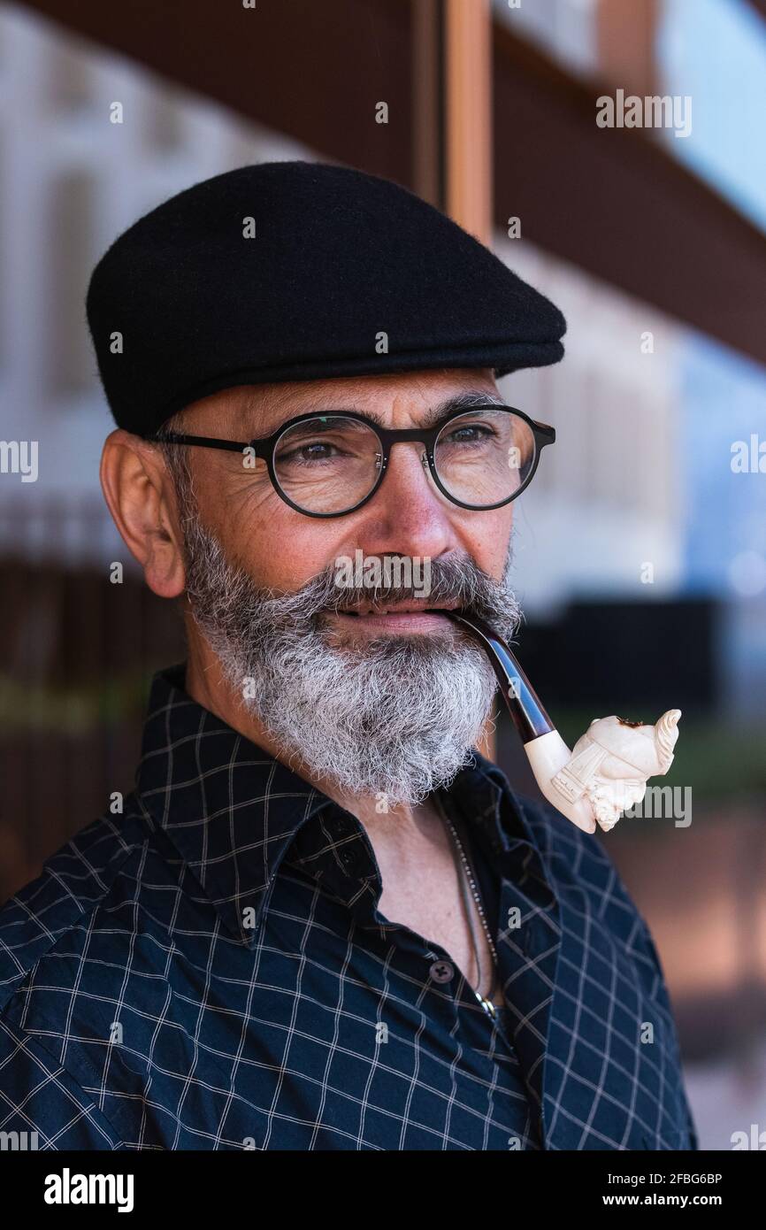 Homme mûr barbu avec tuyau de fumée en regardant loin Banque D'Images