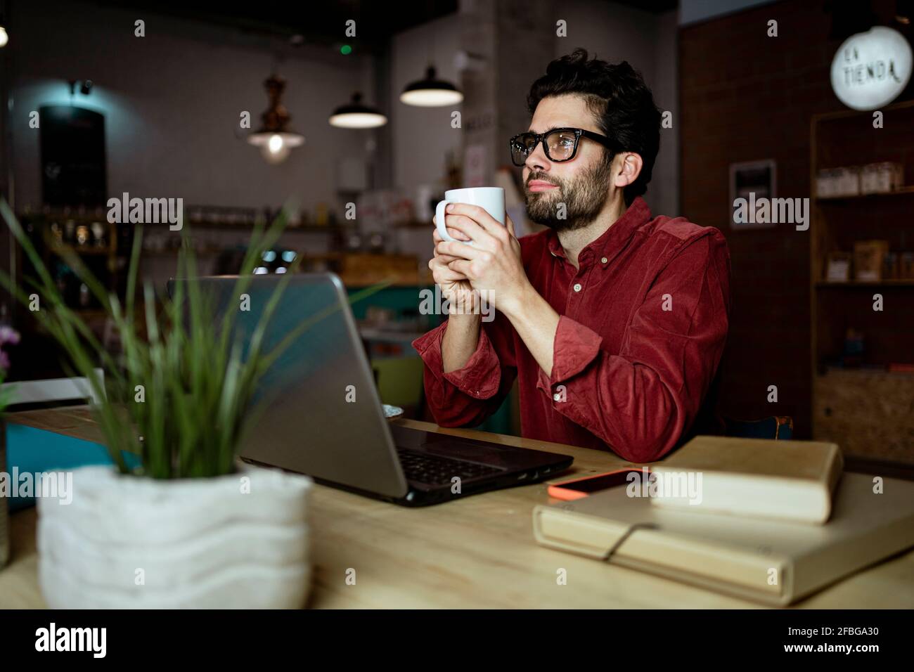 Travailleur indépendant professionnel attentionné avec ordinateur portable et café allumé café Banque D'Images
