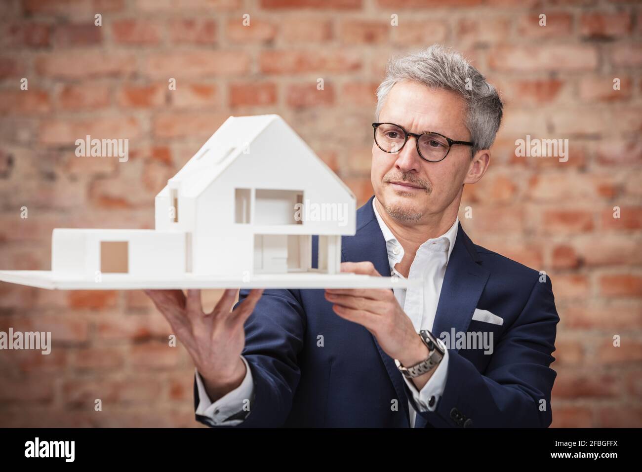Homme d'affaires mature qui planifie tout en regardant la maison modèle au travail placer Banque D'Images