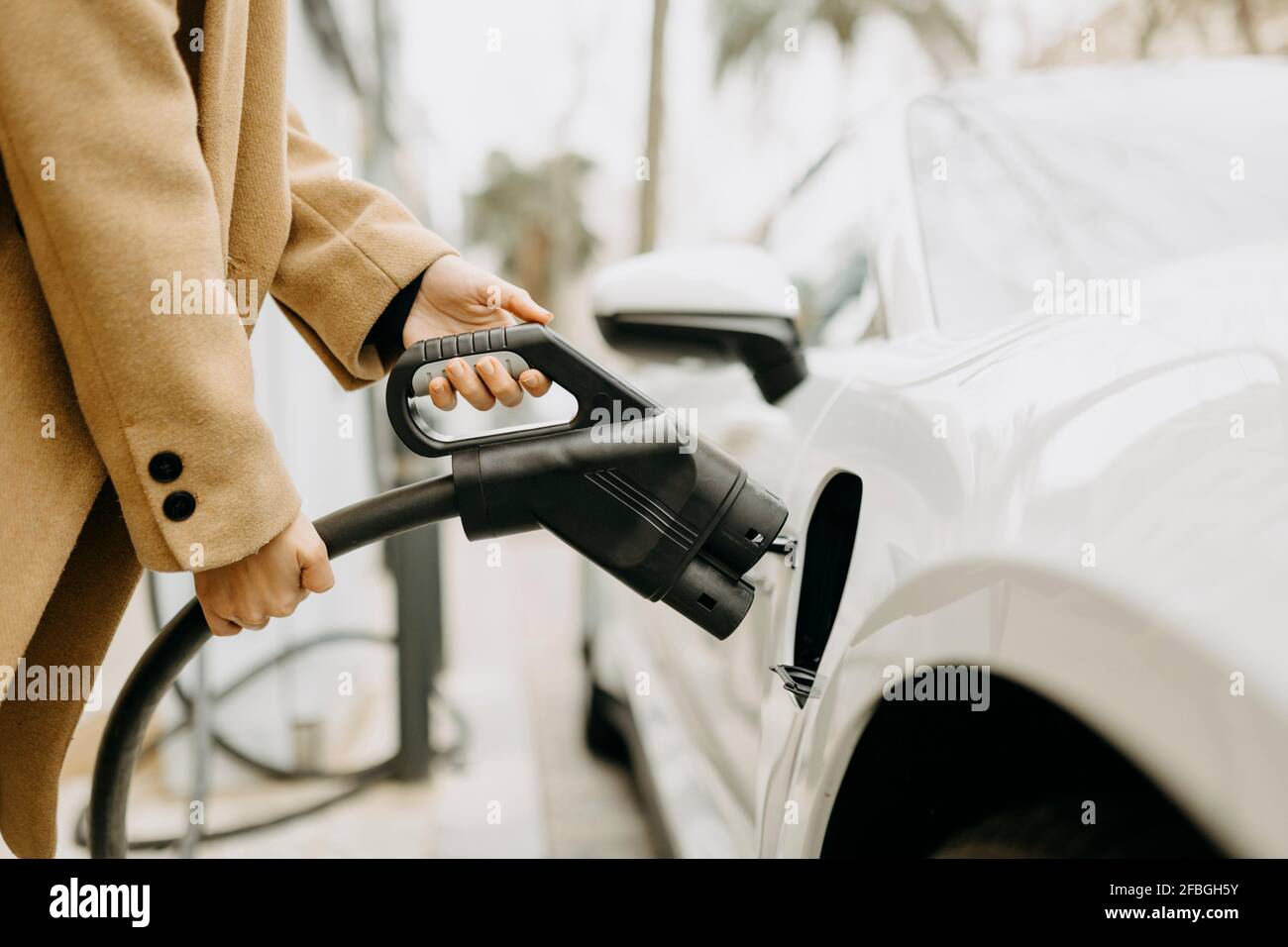 Femme en charge de voiture électrique à la gare Banque D'Images