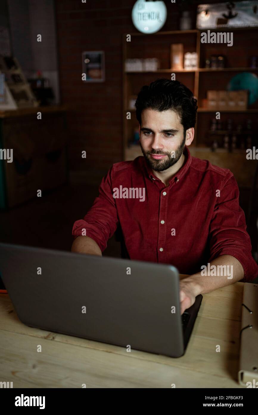Travailleur indépendant travaillant sur un ordinateur portable tout en étant assis dans un café boutique Banque D'Images