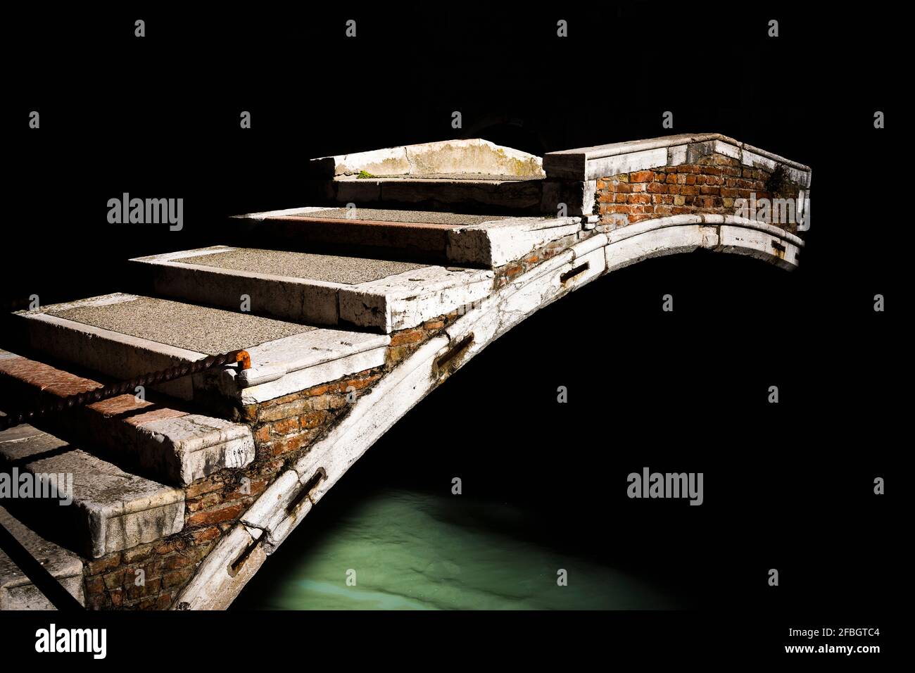 Italie, Vénétie, Venise, Pont de la vieille arche s'étendant sur le canal sombre de la ville Banque D'Images