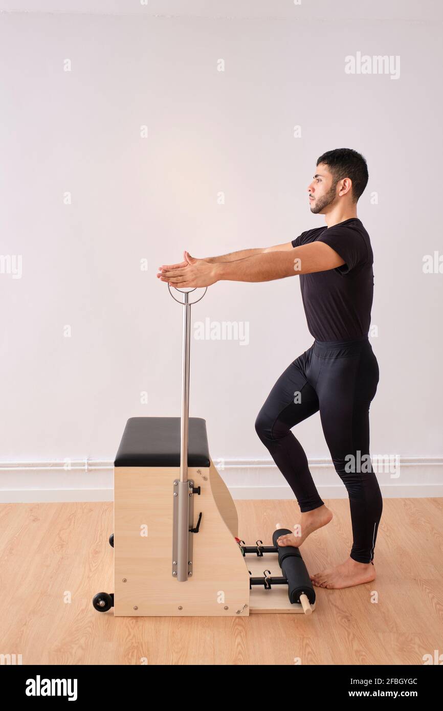 Homme de taille moyenne pratiquant le pilates sur une chaise dans la salle d'exercice Banque D'Images