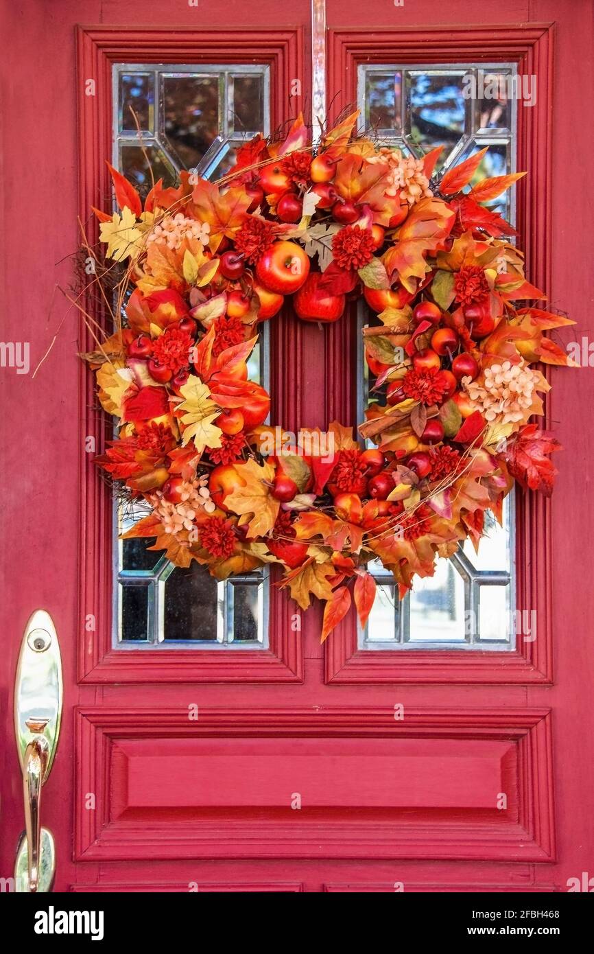 Porte rouge avec fenêtres en verre au plomb et couronne d'automne lumineuse - gros plan Banque D'Images