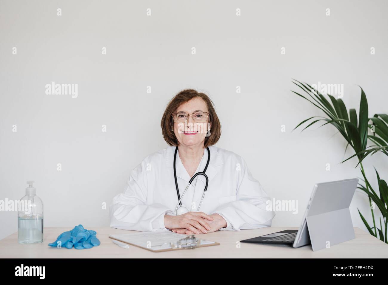 Femme médecin séchée devant le mur blanc à bureau Banque D'Images