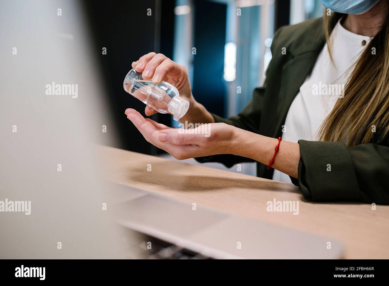 Femme utilisant un désinfectant pour les mains au bureau Banque D'Images