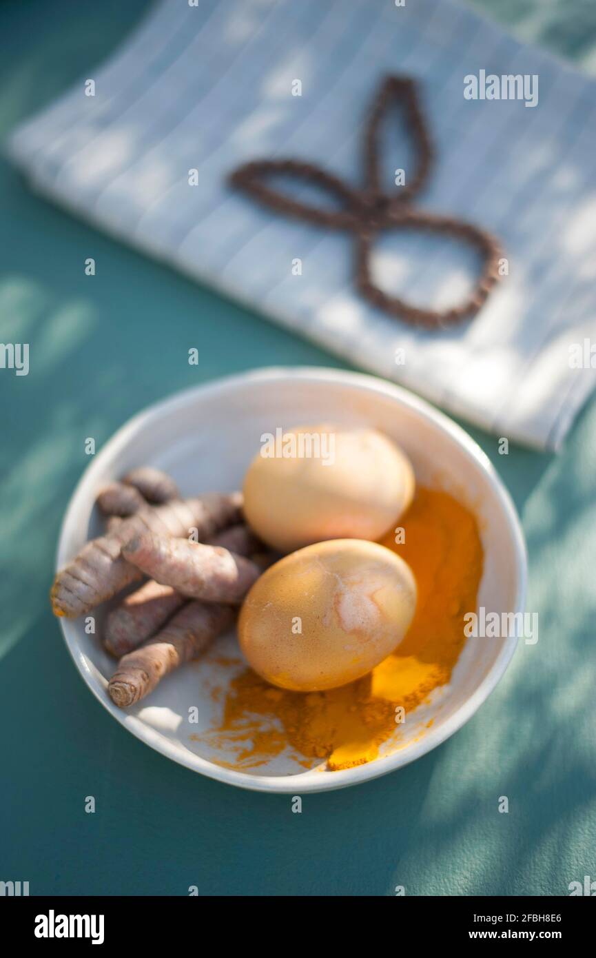Bol avec racines curcuma, poudre curcuma et œufs de Pâques non peints Banque D'Images