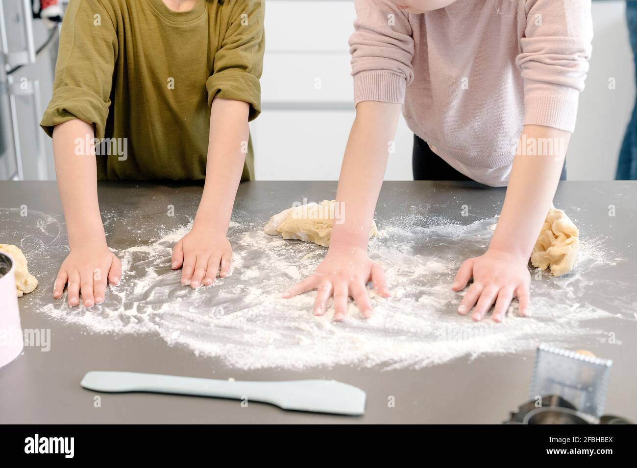 Les enfants répandant de la farine sur l'île de cuisine à la maison Banque D'Images