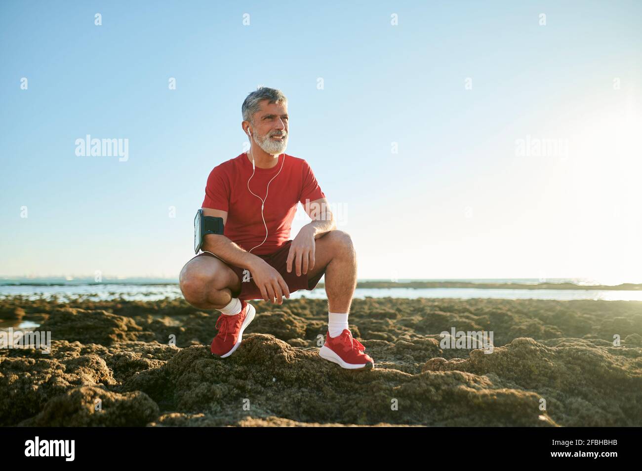 Homme se brouiller sur des rochers à la plage Banque D'Images