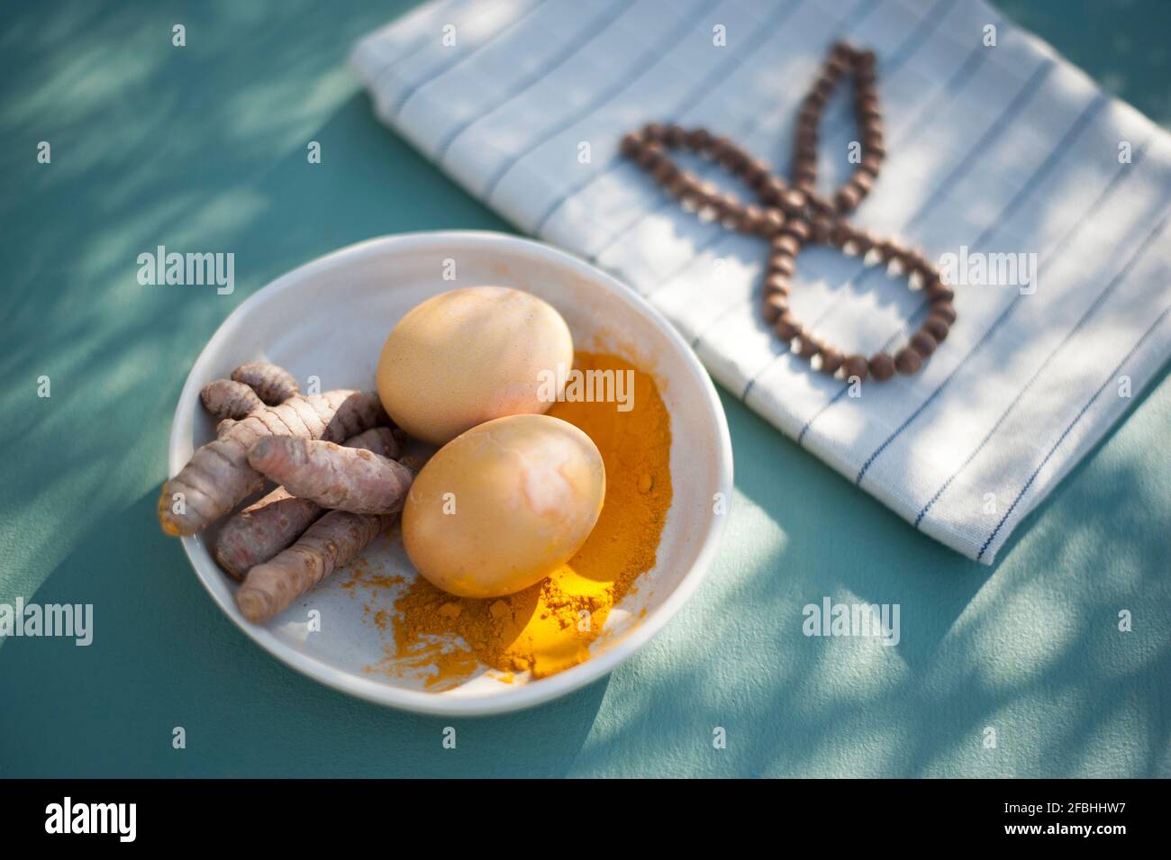 Bol avec racines curcuma, poudre curcuma et œufs de Pâques non peints Banque D'Images