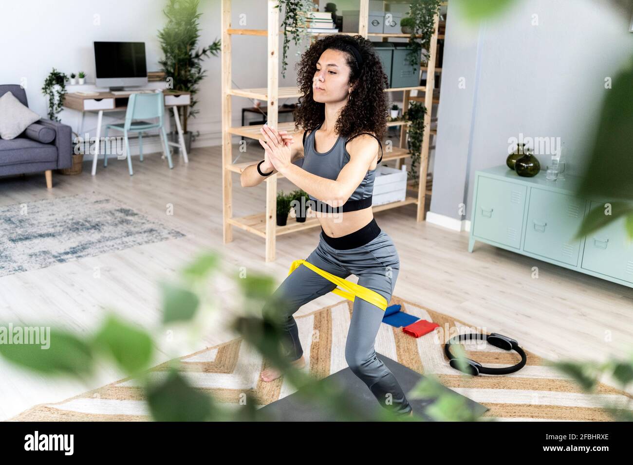 Belle femme avec les mains clasped s'exerçant avec bande de résistance à accueil Banque D'Images