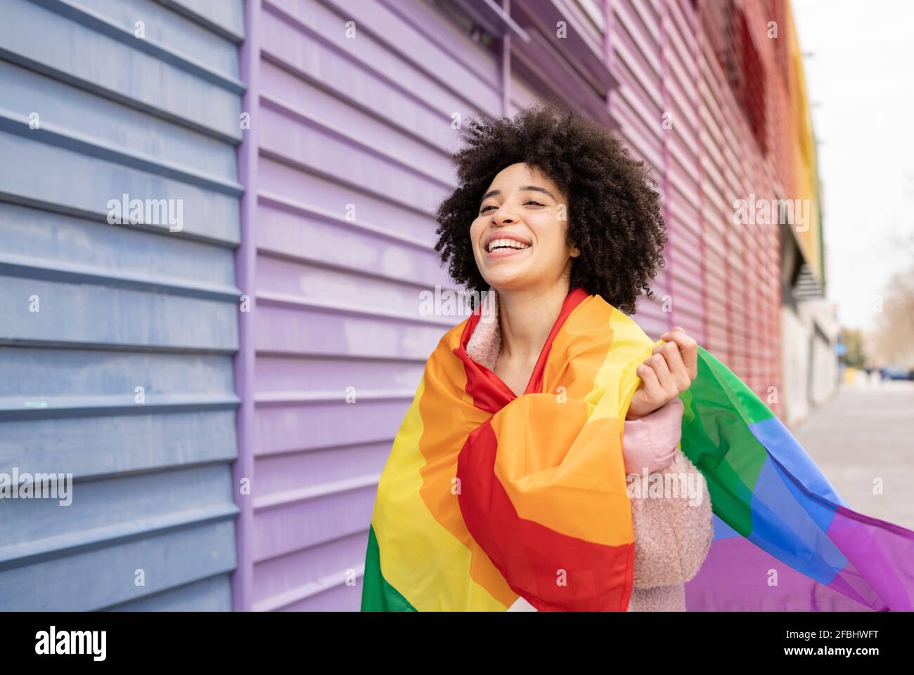 Femme joyeuse enveloppée d'un drapeau arc-en-ciel Banque D'Images