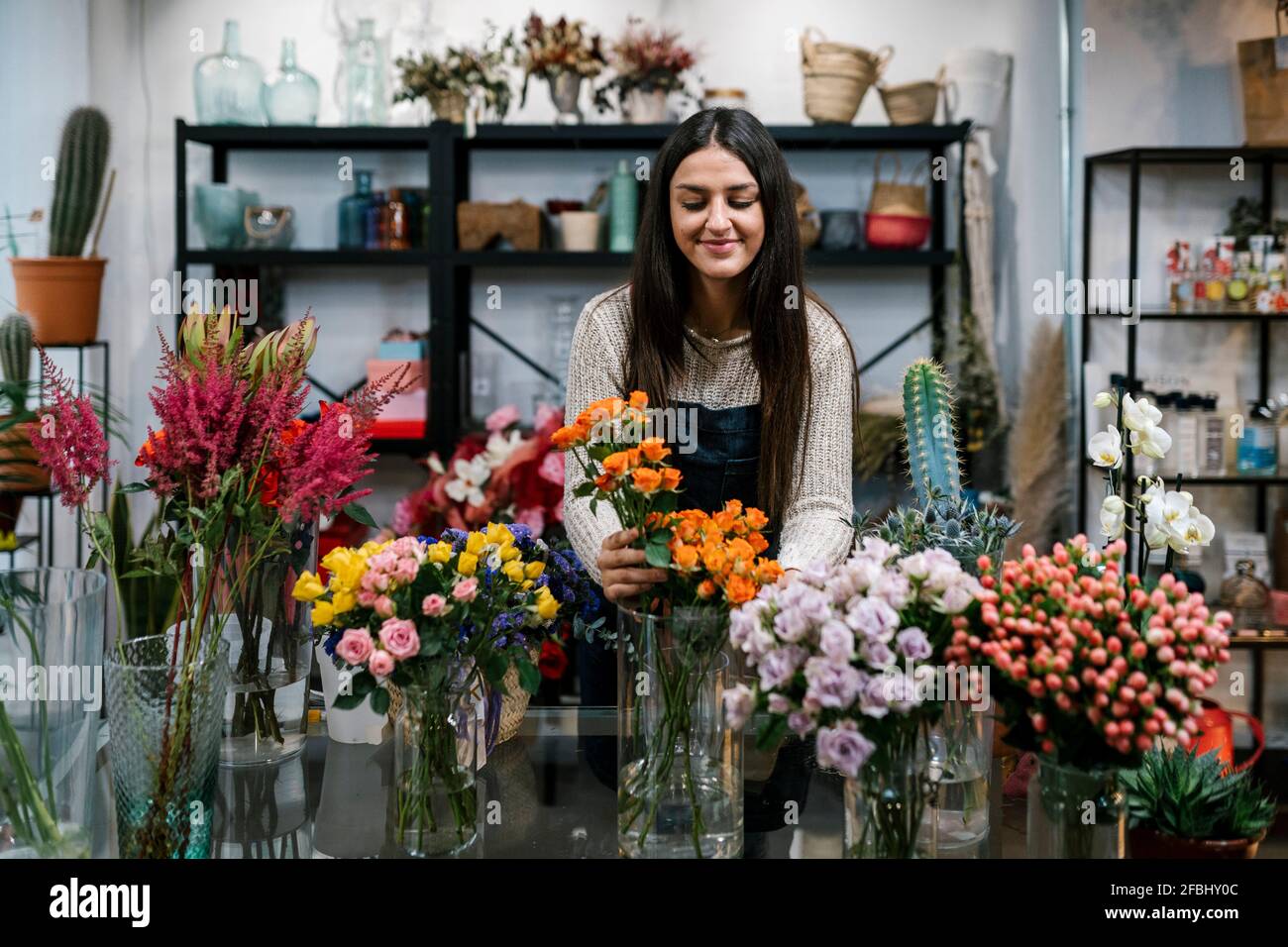 Jeune fleuriste femme organisant des fleurs au magasin Banque D'Images