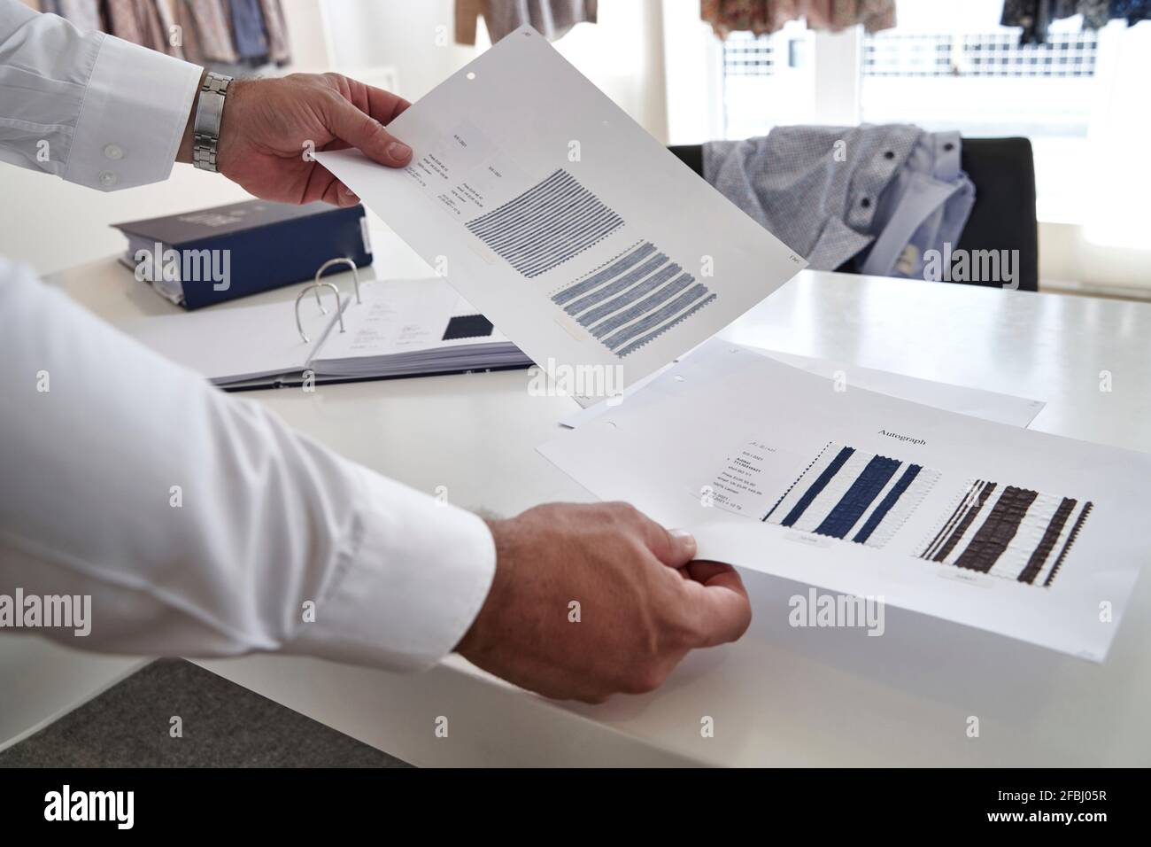 Homme mature tenant un échantillon de tissu sur la table dans la conception de vêtements studio Banque D'Images