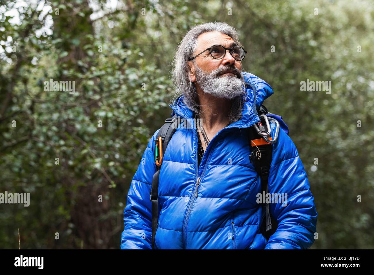 Homme âgé avec des cheveux gris regardant loin dans la forêt Banque D'Images