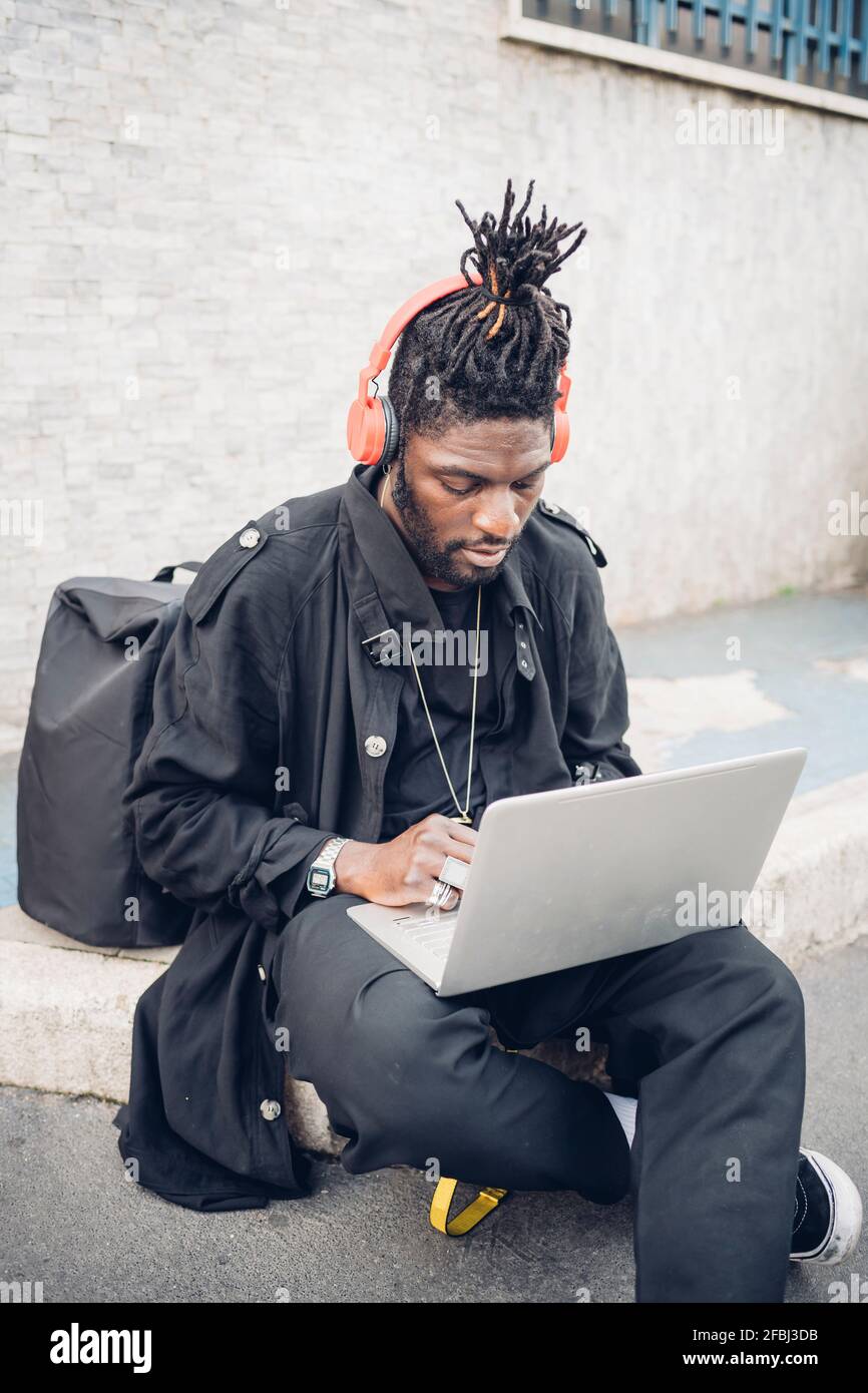 Travailleur indépendant avec casque utilisant un ordinateur portable lorsqu'il est assis chemin de pied Banque D'Images