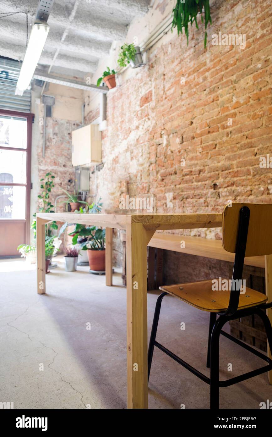 Chaise et table vide à l'intérieur devant la brique mur Banque D'Images