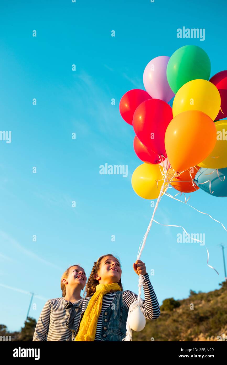 Des filles gaies jouant avec des ballons d'hélium colorés Banque D'Images