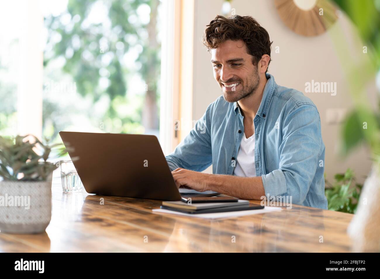 Travailleur indépendant souriant utilisant un ordinateur portable assis à une table Banque D'Images