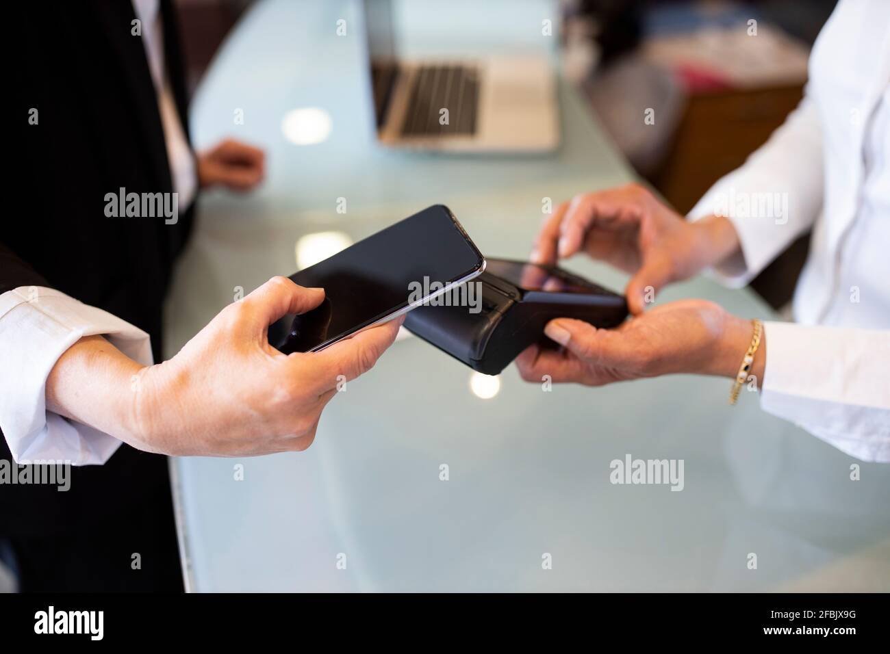 Réceptionniste tenant un lecteur de carte de crédit tout en faisant sans contact avec le client paiement à la réception de l'hôtel Banque D'Images