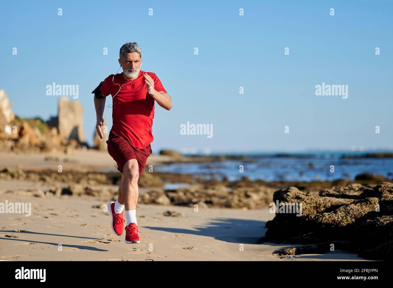 Homme déterminé courant sur la plage pendant la journée ensoleillée Banque D'Images