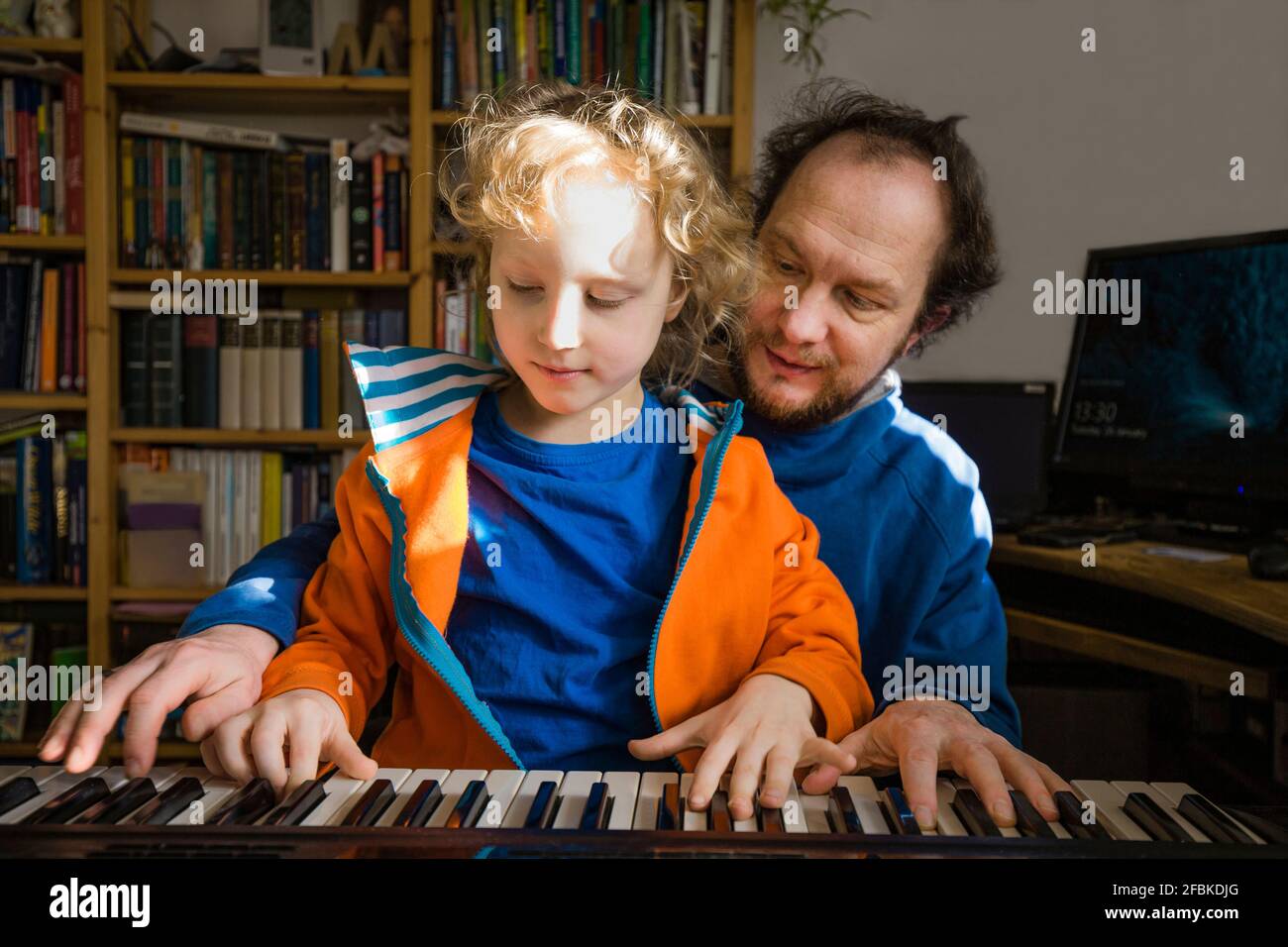 Père enseignant synthétiseur à son fils pendant qu'il est à la maison Banque D'Images
