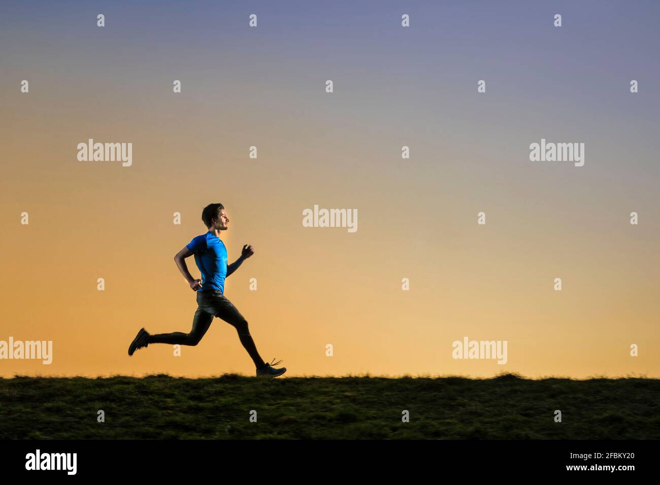 Un sportif qui fait du jogging avec dévouement pendant le coucher du soleil Banque D'Images