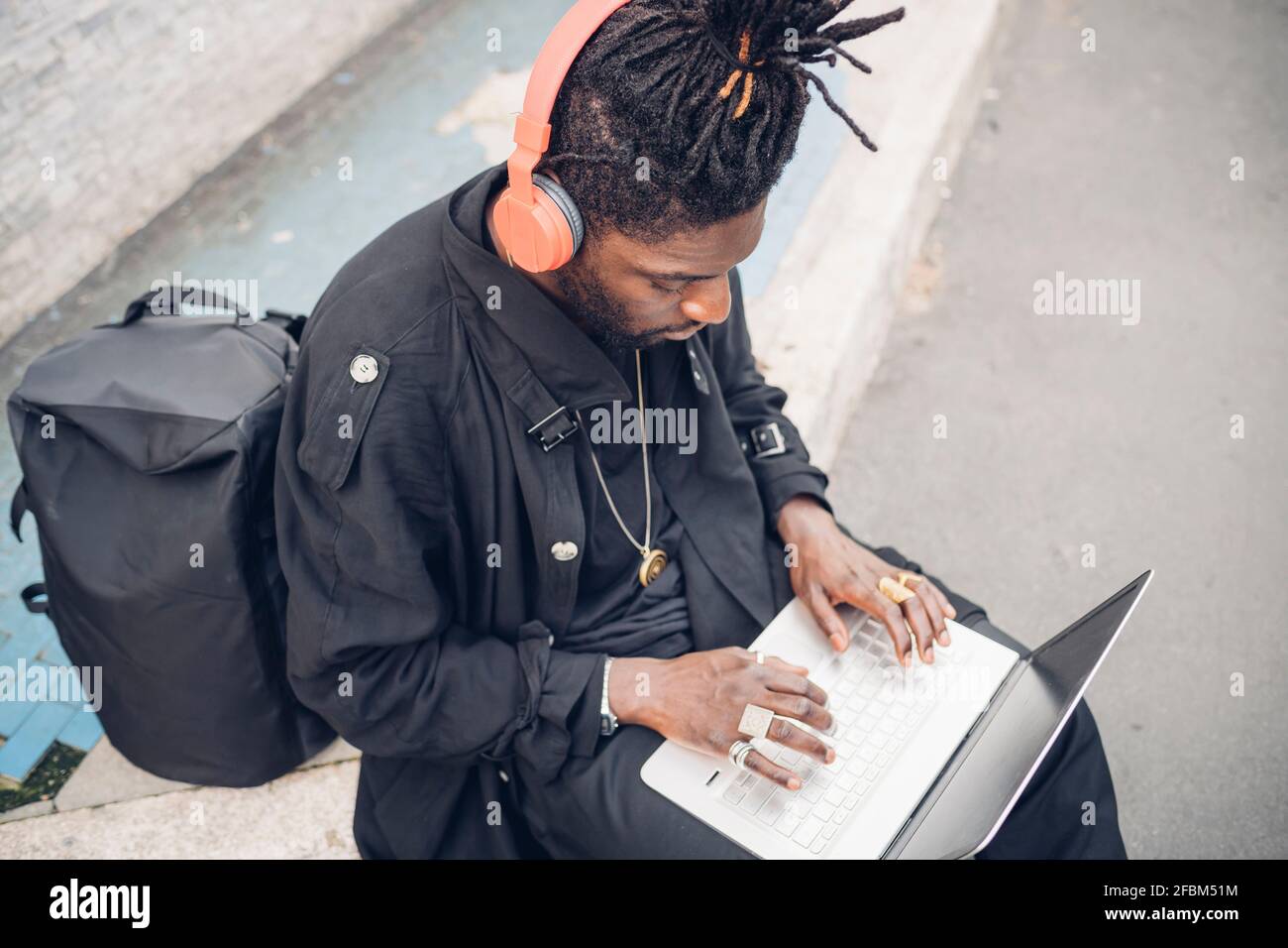 Jeune travailleur indépendant avec un casque utilisant un ordinateur portable lorsqu'il est assis chemin de pied Banque D'Images