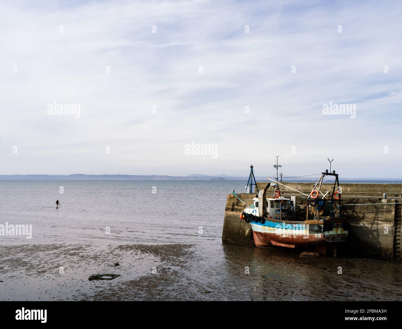 Le chalutier de crevettes s'est attaché à l'entrée du port à marée basse à Fisherrow, près d'Édimbourg, avec quelqu'un qui a un pigeon de retour dans l'eau. Banque D'Images