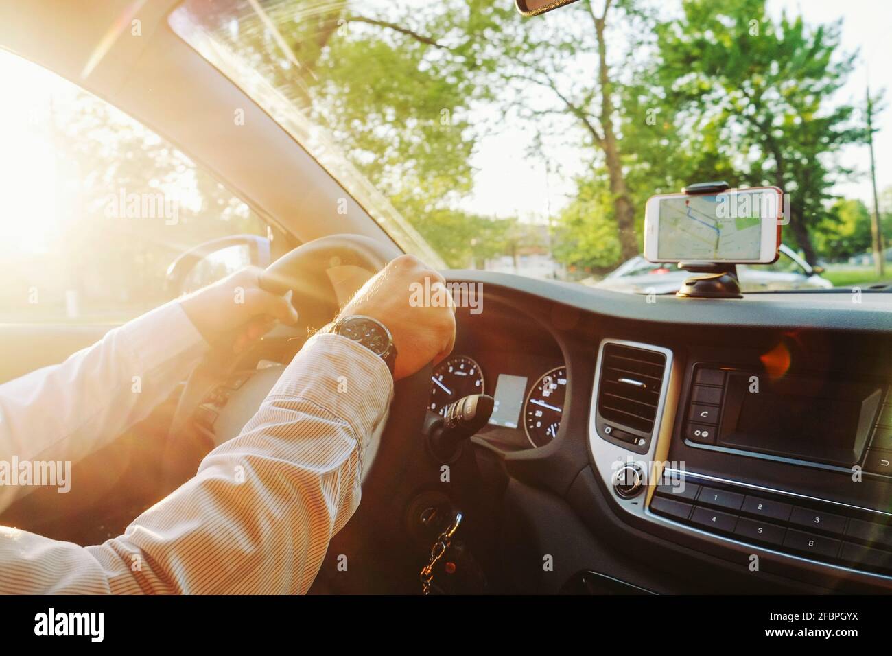 Directives sur le téléphone cellulaire dans le support de téléphone se montent sur la surface du tableau de bord, intérieur coûteux du véhicule. Concept de navigation par itinéraire GPS. Jeune homme ha Banque D'Images