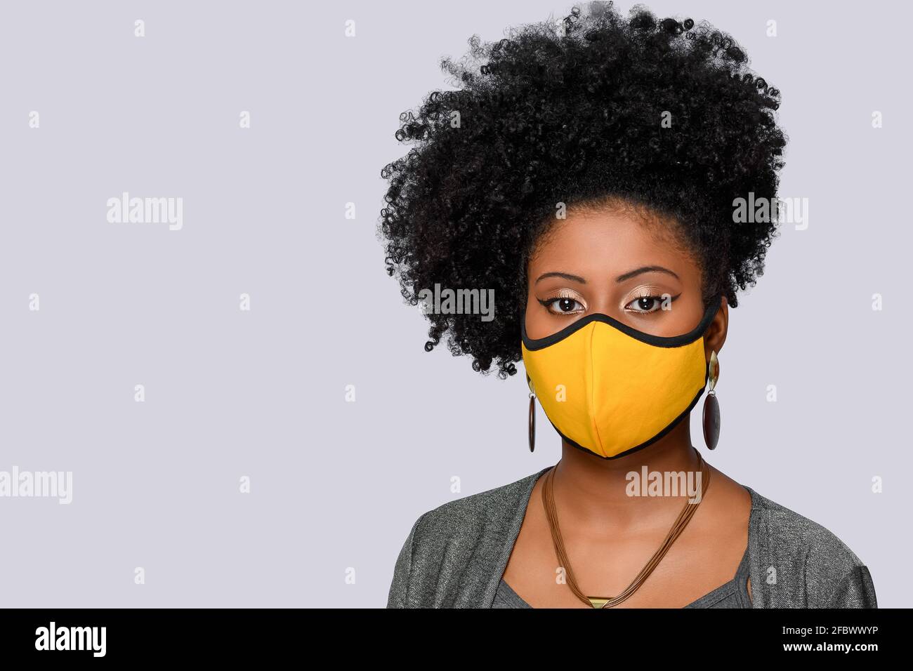 jeune fille aux cheveux de style afro portant un masque de protection contre le coronavirus isolé covid-19 sur fond gris Banque D'Images