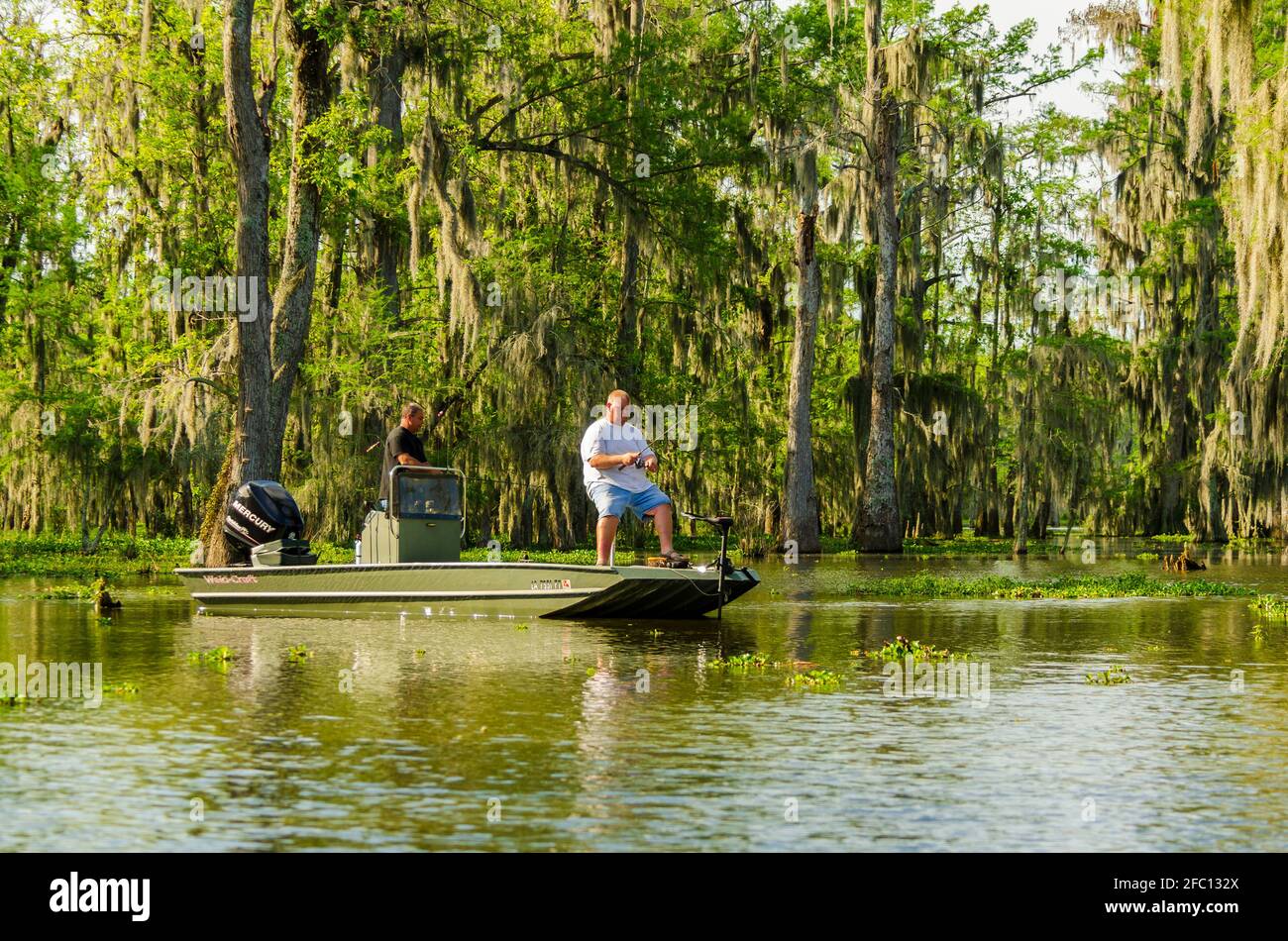 Deux hommes caucasiens pêchant dans un bateau à basse dans le marécage du bassin de l'Atchafalaya en Louisiane, aux États-Unis. Banque D'Images