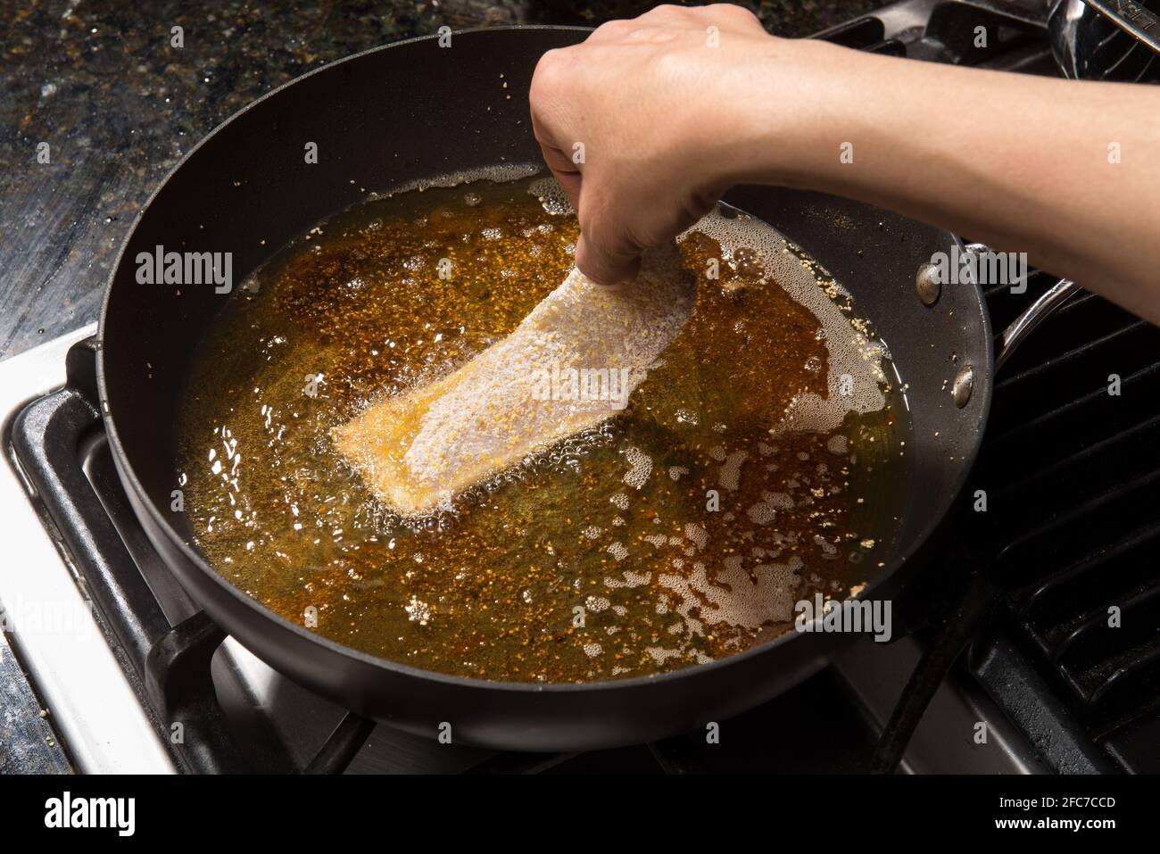 Faire frire à la poêle ou faire cuire à la maison du filet de poisson sur une cuisinière. Banque D'Images