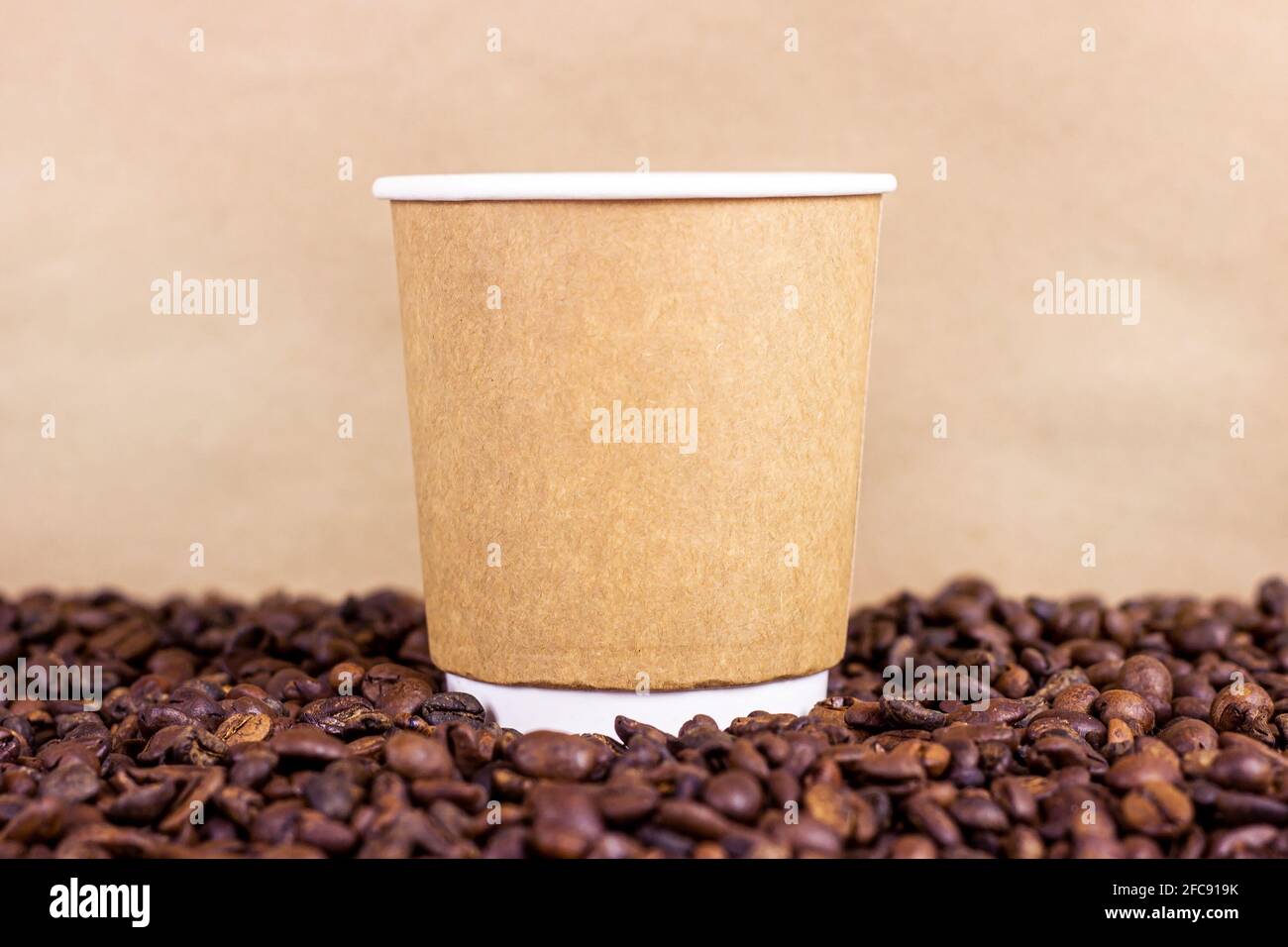 Tasse jetable en carton brun avec café et grains de café rôtis sur la table avec espace de copie sur fond clair. Concept de plats à emporter. Banque D'Images