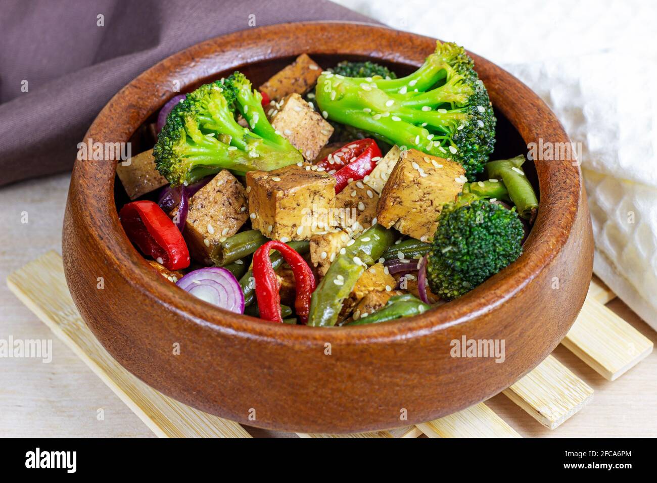 Tofu plat végétarien fait maison avec des légumes (brocoli, poivre, oignons et haricots verts) dans le bol en bois. Banque D'Images