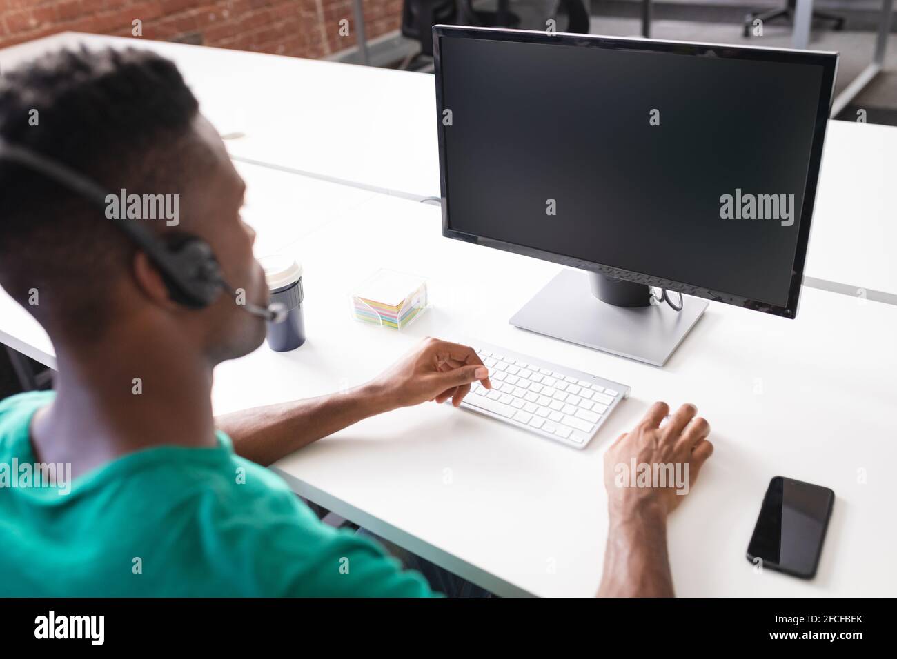 Homme d'affaires afro-américain ayant la vidéoconférence devant ordinateur utilisant un casque Banque D'Images