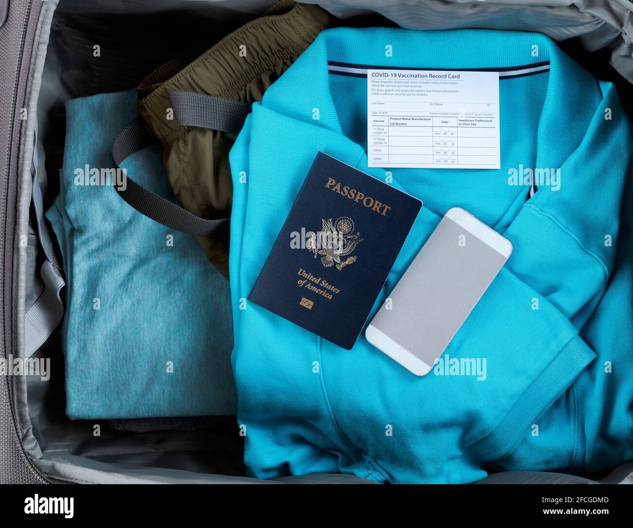 Livre de passeport des États-Unis avec carte de vaccination Covid 19 et smartphone à l'intérieur de la valise de voyage remplie de vêtements Banque D'Images Livre de passeport des États-Unis avec carte de vaccination Covid 19 et smartphone à l'intérieur de la valise de voyage remplie de vêtements Banque D'Images