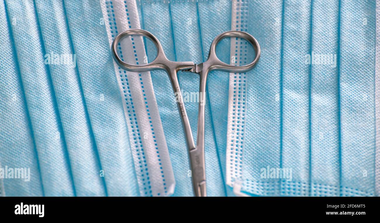 Ciseaux de forceps hémostatiques sur le dessus des masques chirurgicaux photographie rapprochée. Banque D'Images