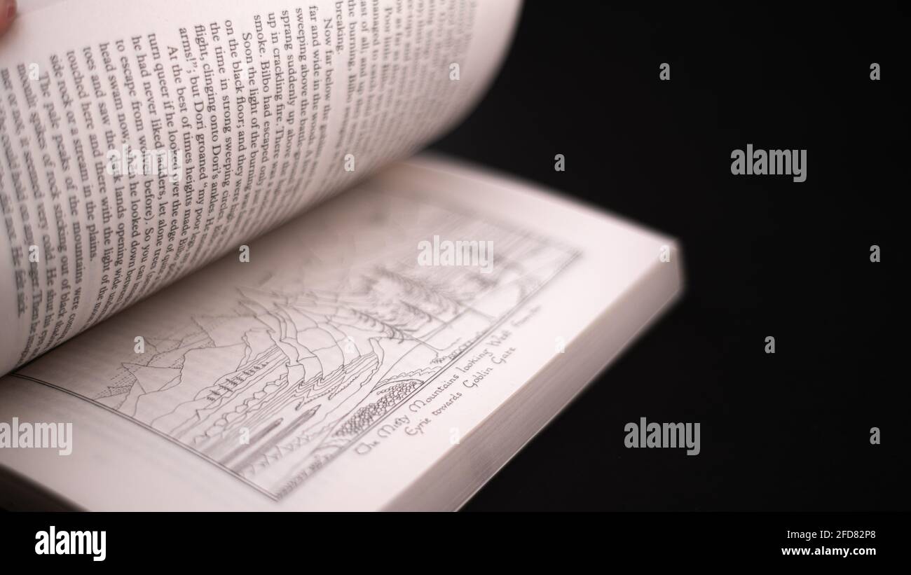Pages défilant du célèbre roman The Hobbit de J.R.R.Tolkein. Livre ouvert isolé dans un fond noir foncé. Con Banque D'Images