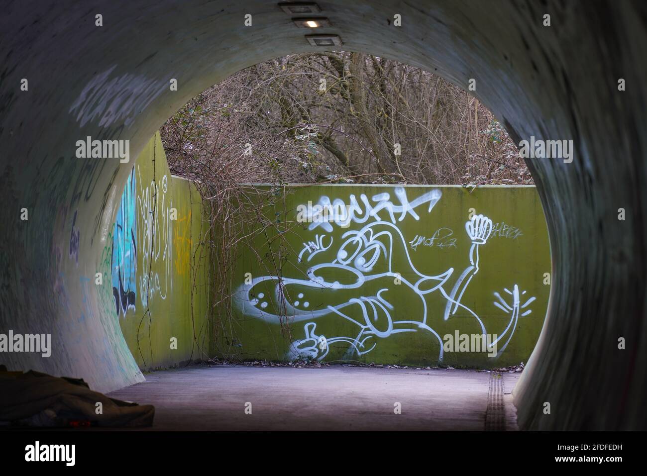 Métro, sous-pass, projecteurs, effrayant, nuit, voyageur seul, coupe courte, tunnel rond, lien vers le sol, béton, graffiti, art mural, Banksy, tag. Banque D'Images