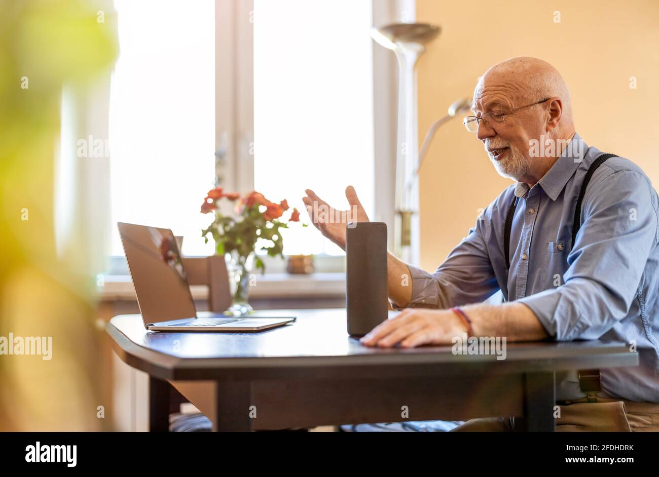 Homme senior utilisant Virtual Assistant à la maison Banque D'Images
