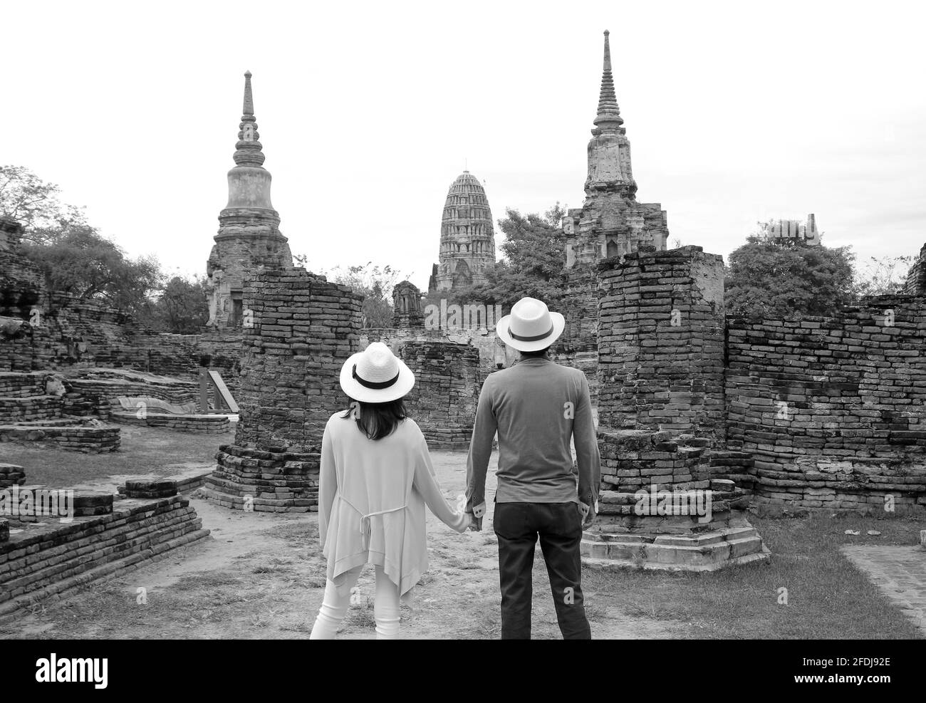 Image monochrome d'un jeune couple visitant les incroyables ruines du temple dans le parc historique d'Ayutthaya, région centrale de la Thaïlande Banque D'Images