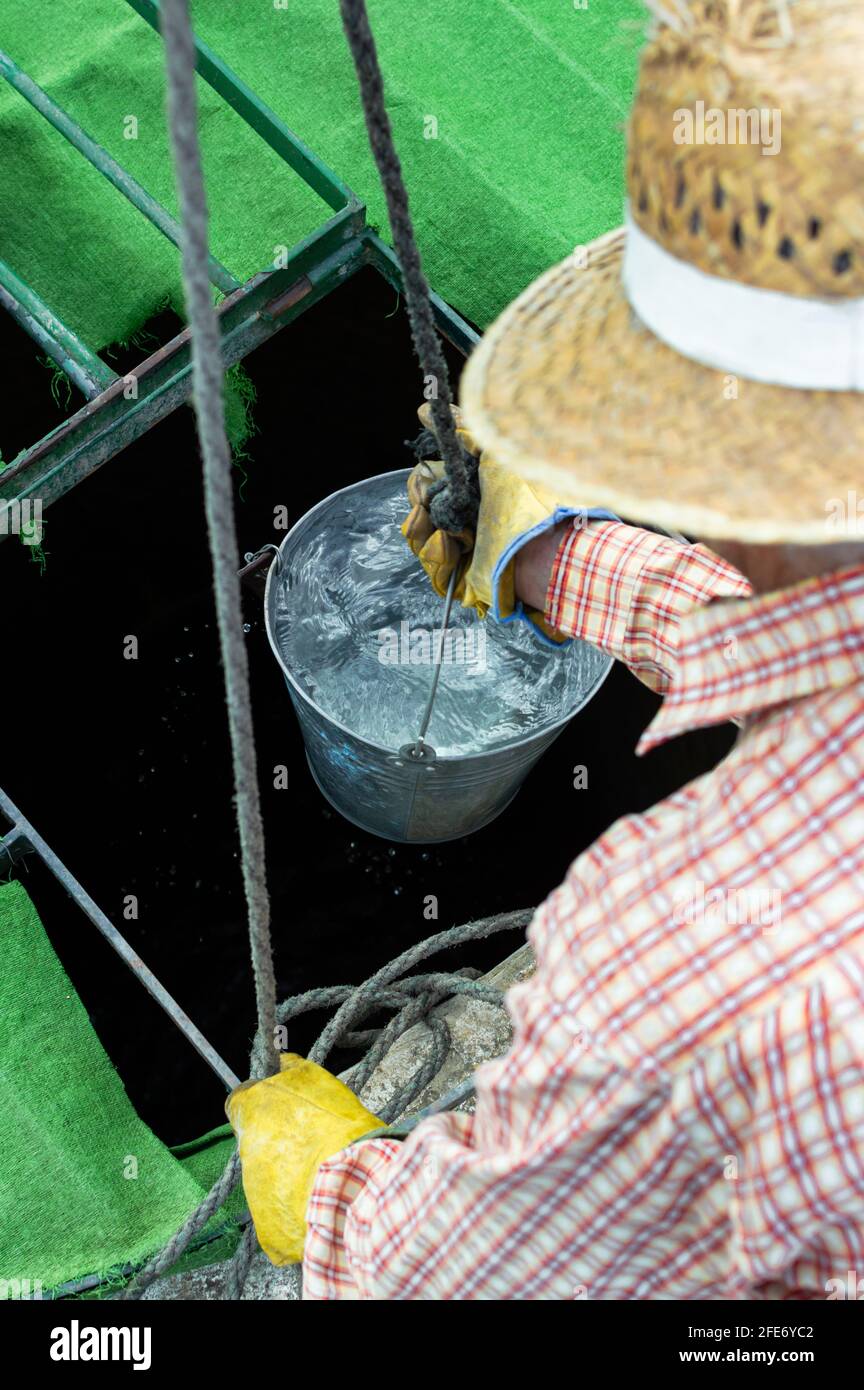 Fermier avec chapeau de paille tirant de l'eau fraîche d'un puits dans le  contryside Photo Stock - Alamy